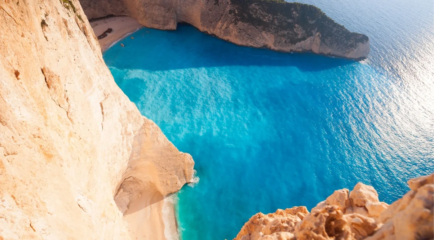Close aerial detail of ochre and white limestone cliffs dropping into vivid turquoise water