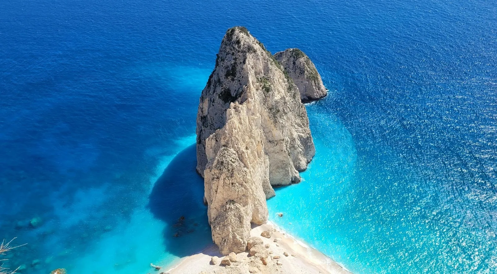 A tall sea stack rising from deep blue water off the north coast of Zakynthos